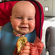Swan participe au concours pour gagner de l'argent avec cette photo : baby, child, high_chair, food, crumbs, smiling, bib, hand, face, indoor, eating, happy, chubby_cheeks, clothing, red, striped, kitchen, furniture, person, portrait