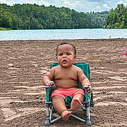 Ryker joined the competition — help win amazing prizes! toddler, child, beach, sand, lake, water, trees, sky, clouds, greenery, swim_trunks, chair, outdoor, nature, summer, barefoot, portrait, sitting, curious, vacation