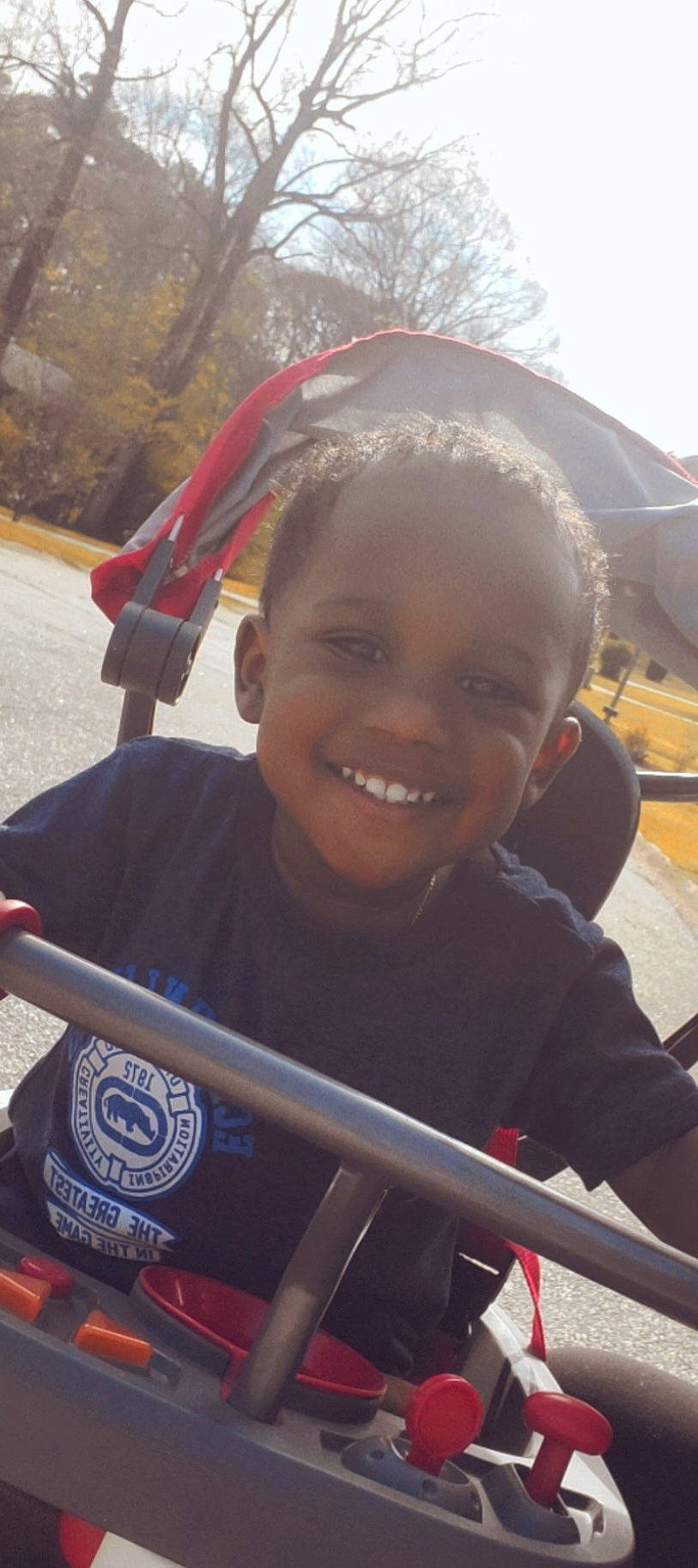 Jacoby is registered to the contest to win money with this photo: child, cool, eye, fun, grass, happy, joy, laugh, leisure, person, personal_protective_equipment, recreation, road_bicycle, sitting, smile, spoke, t_shirt, toddler, travel, tree