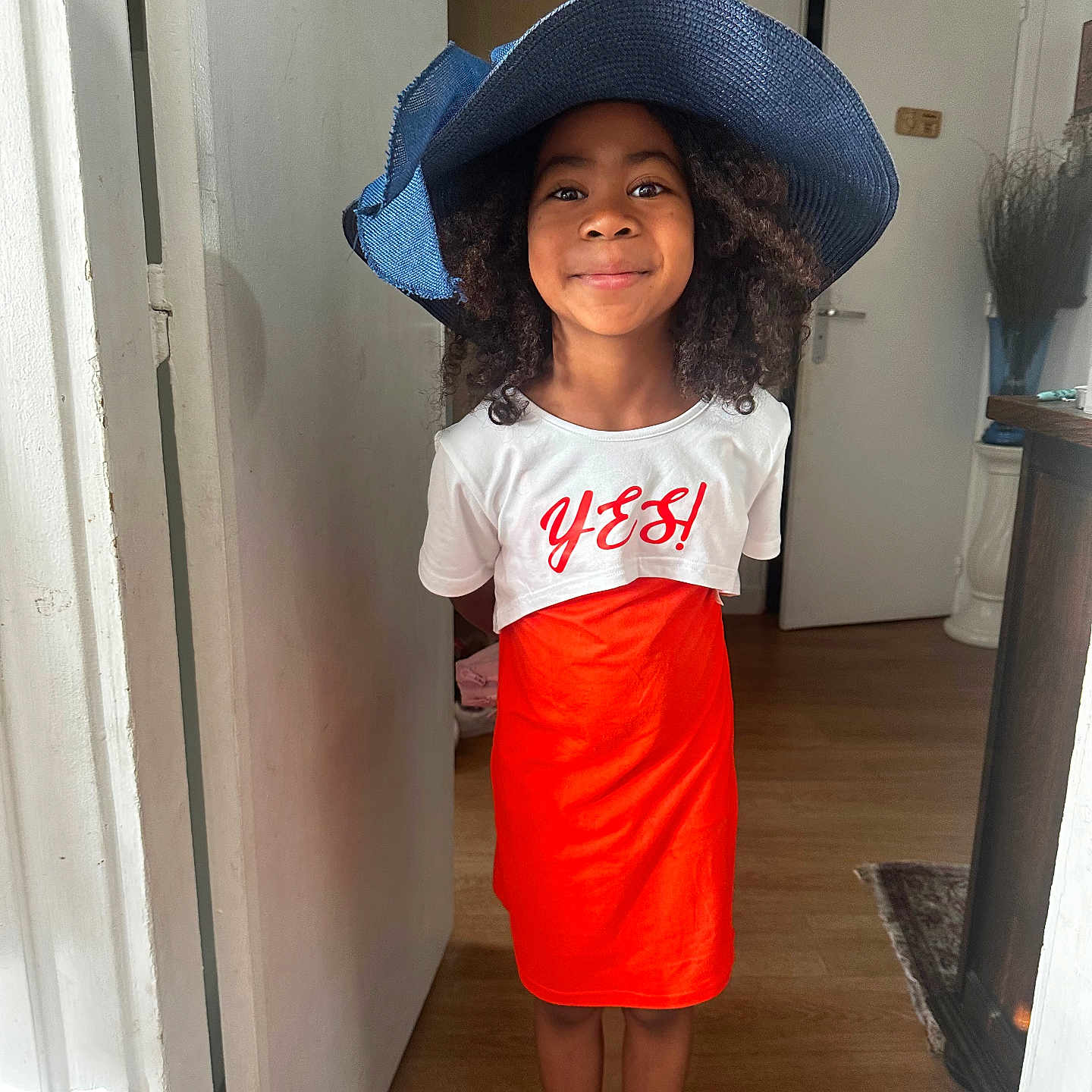 Natacha participe au concours pour gagner de l'argent avec cette photo : child, clothing, costume, cowboyhat, door, dress, face, female, girl, hat, head, pants, person, photography, portrait, skirt, sleeve, standing, sunhat, wood