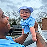 Kareem joined the competition — help win amazing prizes! baby, man, smile, outdoor, cloudy_sky, tree, truck, brick_building, tattoo, hat, blue_clothing, happy, holding, person, portrait, daylight, casual, father_and_child, joy, family