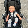 Kareem is registered to the contest to win money with this photo: baby, child, stroller, smile, happy, outdoor, pavement, clothing, infant, seatbelt, person, footwear, sock, cute, portrait, babywear, transport, wheel, hand, head