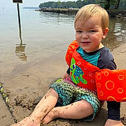 Luca joined the competition — help win amazing prizes! child, beach, sand, water, floatie, life_jacket, toddler, swimwear, lake, shore, trees, sign, sunny, outdoor, summer, play, sitting, happy, cute, fun
