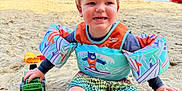 Luca is registered to the contest to win money with this photo: toddler, child, beach, sand, water, lake, floaties, toy, truck, yellow_flag, summer, outdoor, happy, playing, barefoot, shorts, swimwear, sunny, sky, nature