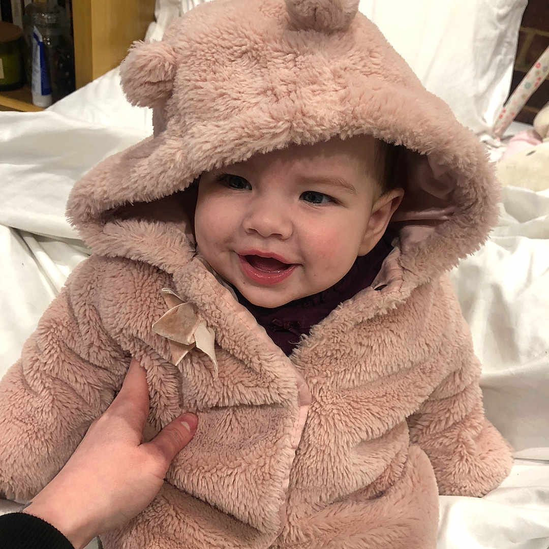 Aella is registered to the contest to win money with this photo: baby, blanket, bodypart, bonnet, clothing, coat, face, finger, hand, happy, hat, head, hood, hoodie, knitwear, person, photography, portrait, sweater, sweatshirt
