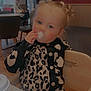 toddler, child, pacifier, highchair, leopard_print, sweater, indoor, cafe, wooden_furniture, table, cup, curly_hair, earrings, person, face, seated, cute, blond_hair, expression, background