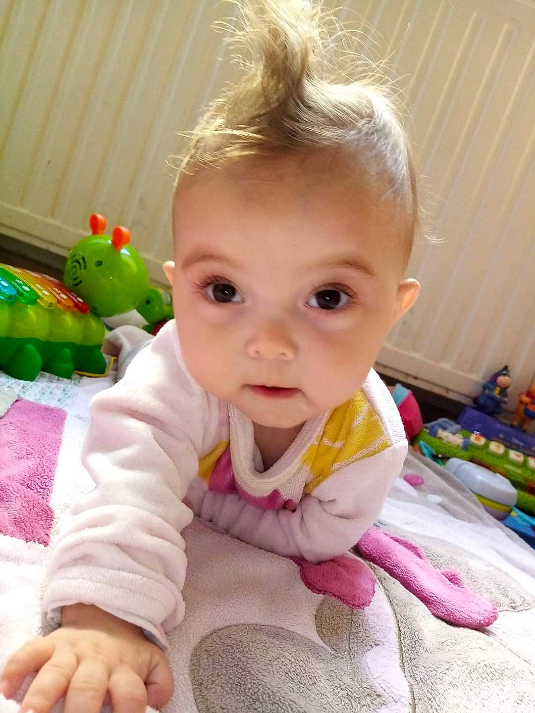 Luccia participe au concours pour gagner de l'argent avec cette photo : baby, baby_products, baby_toddler_clothing, cheek, child, dress, finger, flooring, hair, hand, happy, human_body, iris, lip, nose, person, pink, skin, sleeve, toddler