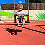 Leeroy a rejoint le concours — aidez-le/la à gagner de superbes lots ! toddler, child, swing, playground, smiling, curly_hair, outdoor, sunny, shadow, red_ground, blue_sky, graffiti, fence, shorts, tshirt, sandals, happy, daytime, person, play