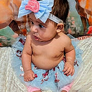 Gracie is registered to the contest to win money with this photo: baby, child, tutu, bow, headband, bare_chest, sitting, blanket, curious, indoors, footwear_none, pink_pants, cute, infant, portrait, decorative_background, animal_painting, soft_texture, skin, person