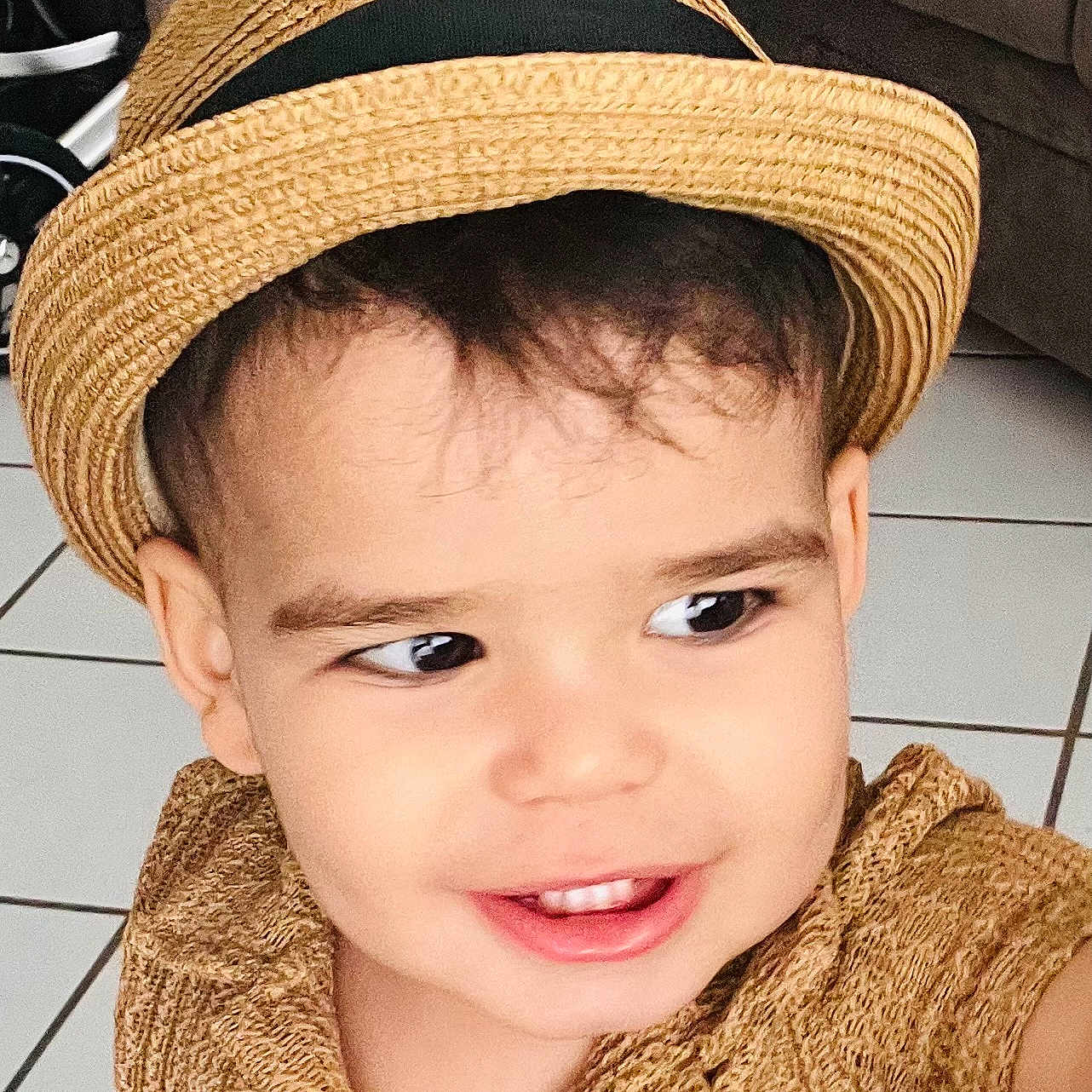 Aslan Castano joined the competition — help win amazing prizes! brown_clothing, child, couch, curly_hair, cute, face, floor_tiles, happy, hat, headwear, indoors, living_room, person, playful, portrait, smile, straw_hat, textured_fabric, toddler, young_child