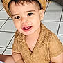 toddler, child, hat, straw_hat, smile, indoor, tile_floor, watch, smartwatch, shirt, beige, cute, person, happy, baby, arm, toy, furniture, living_room, casual