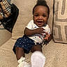 baby, child, smiling, sitting, couch, white_shoes, star_pattern, clothing, happy, indoor, foot, person, cute, infant, young_child, textile, furniture, sock, hand, portrait