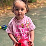 child, toddler, curly_hair, blue_eyes, red_soccer_ball, pink_tshirt, ice_cream_graphic, outdoor, autumn_leaves, blurred_background, standing, holding, playful, happy, cute, person, daylight, casual_clothing, young, innocent