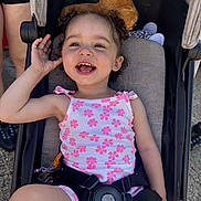 Liana-Mae is registered to the contest to win money with this photo: toddler, child, stroller, smiling, curly_hair, outdoor, sunny, plush_toy, pink_flower_outfit, happy, person, seatbelt, casual_clothing, legs, footwear, daylight, playful, cute, baby, portrait