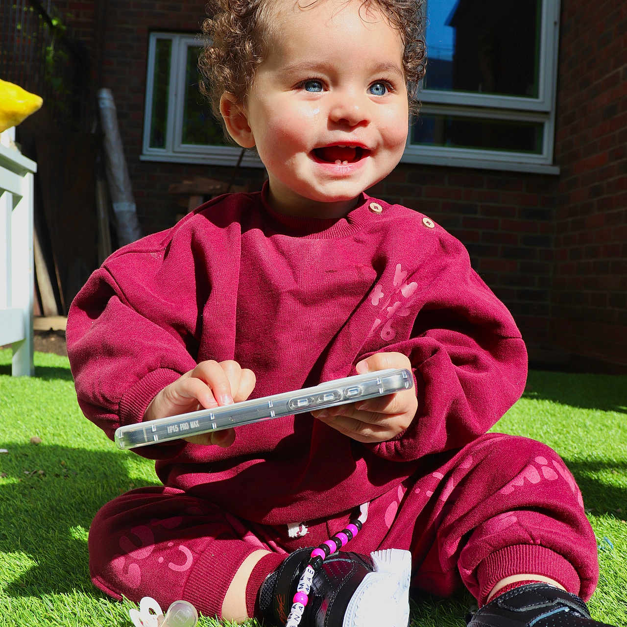 Liana-Mae is registered to the contest to win money with this photo: baby, bodypart, clothing, face, finger, footwear, grass, hand, head, lawn, pants, person, photography, plant, portrait, runningshoe, shoe, sneaker, sword, weapon