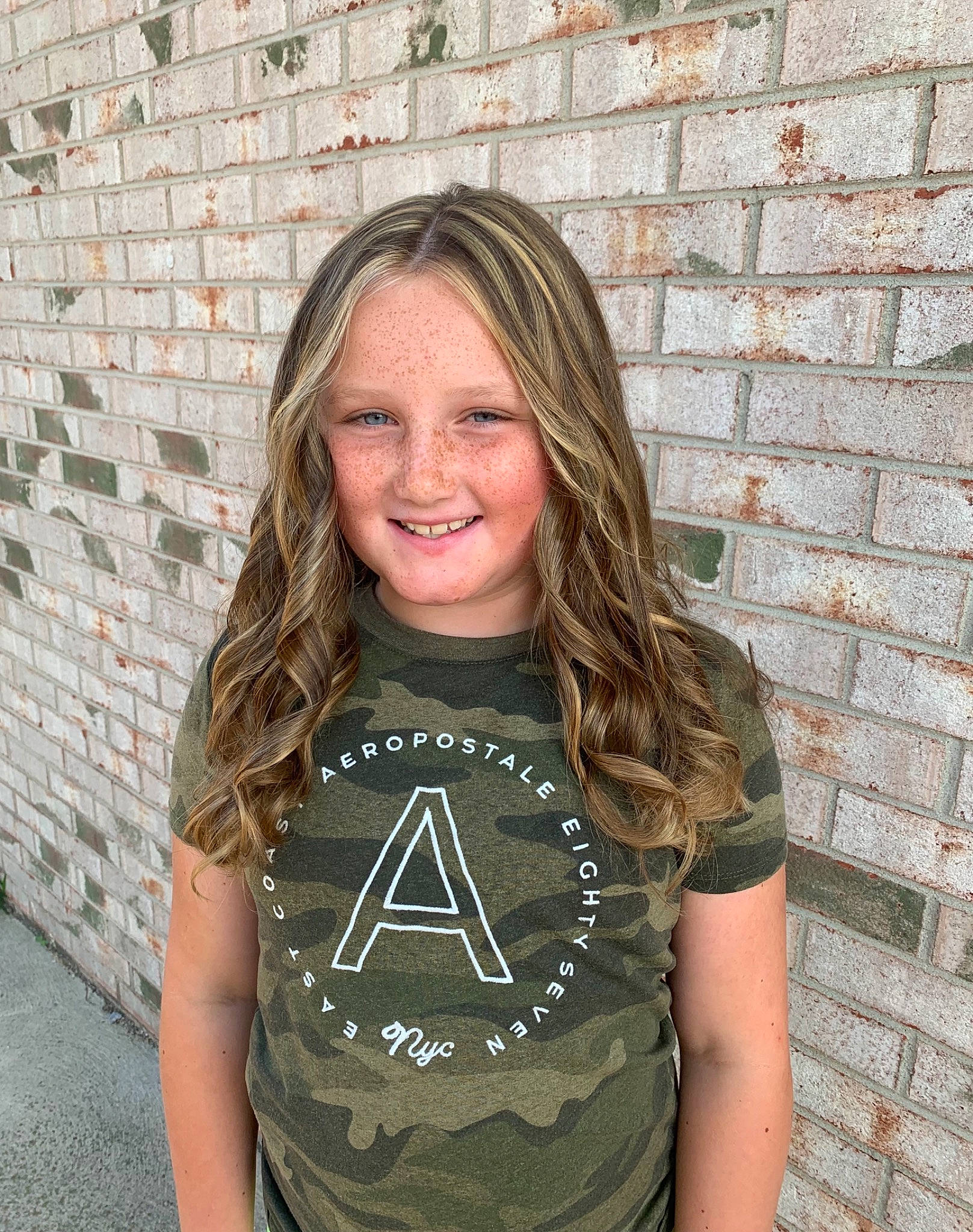 Carly is registered to the contest to win money with this photo: arm, brick, brickwork, cool, facial_expression, flash_photography, grey, hair, happy, human, joint, joy, neck, outerwear, person, shoulder, sleeve, smile, street_fashion, t_shirt