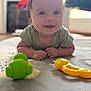 Giulian a rejoint le concours — aidez-le/la à gagner de superbes lots ! baby, carpet, child, close_up, colorful, cute, face, floor, green_toy, happy, indoor, infant, lying_down, pattern, person, playtime, smiling, toddler, toy, yellow_toy