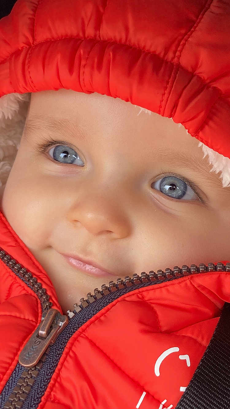 Jonas a rejoint le concours — aidez-le/la à gagner de superbes lots ! baby, child, face, blue_eyes, jacket, red_jacket, zipper, hood, close_up, portrait, cute, smile, skin, eyelashes, winter_clothing, warm_clothing, infant, young_child, expression, outdoor_clothing