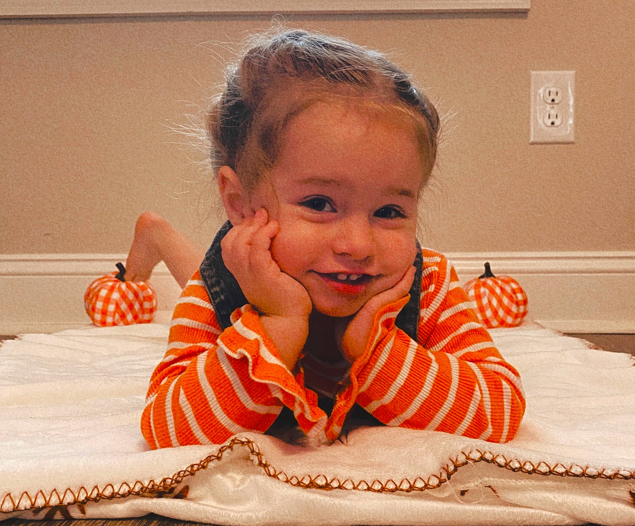 Lilah is registered to the contest to win money with this photo: arm, baby, baby_toddler_clothing, cheek, child, comfort, eyelash, finger, flooring, fun, gesture, happy, joy, nose, orange, person, skin, sleeve, smile, thumb