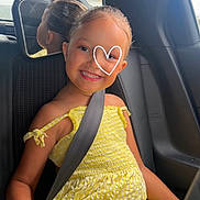 April a rejoint le concours — aidez-le/la à gagner de superbes lots ! child, girl, smiling, yellow_dress, car_seat, seat_belt, reflection, rearview_mirror, happy, portrait, vehicle_interior, casual_clothing, sunlight, hair_tied_back, bracelet, sitting, young, cute, travel, daytime