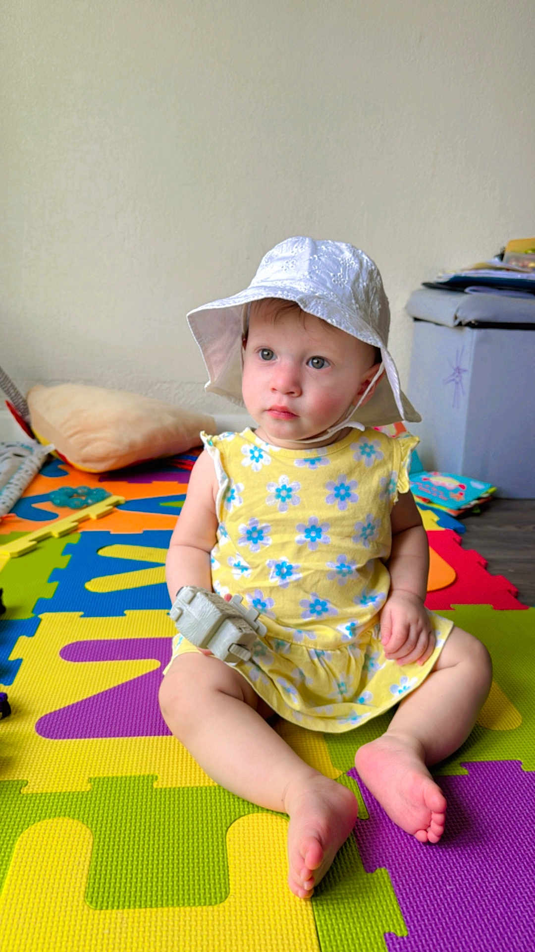 Hadaisha joined the competition — help win amazing prizes! toddler, child, hat, dress, toy, floor_mat, indoor, sitting, colorful, play_area, baby, foot, hand, face, puzzle_mat, yellow, white, blue, flower_pattern, soft_light