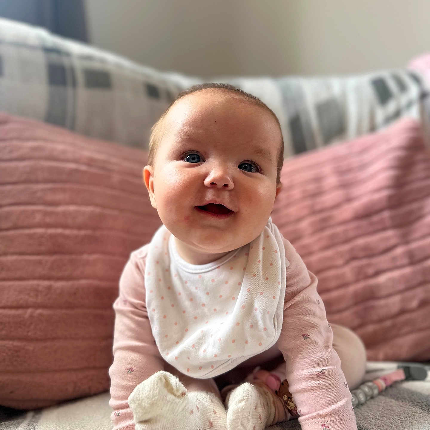 Mabel joined the competition — help win amazing prizes! baby, bib, blanket, child, couch, cozy, crawling, cute, face, hands, happy, indoor, infant, person, pillows, pink_clothing, smiling, socks, soft, young_child