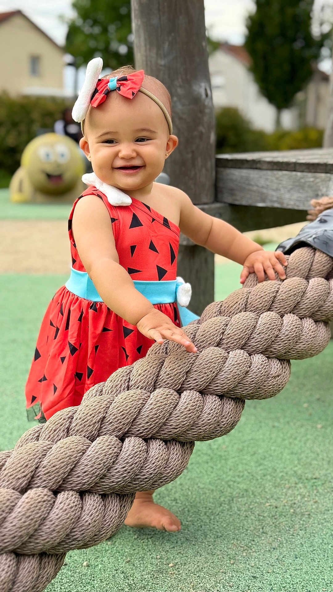 ísis a rejoint le concours — aidez-le/la à gagner de superbes lots ! child, toddler, smiling, outdoor, playground, rope, dress, headband, barefoot, happy, toy, wood, green_ground, daylight, person, nature, fun, cute, recreation, background