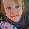 child, toddler, blue_eyes, messy_face, blanket, colorful, patterned, cute, portrait, indoor, clothing, smile, face, hair, person, young_child, snack, happy, close_up, expression