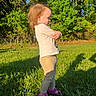 Abigail joined the competition — help win amazing prizes! toddler, child, grass, outdoor, sunlight, shadow, trees, greenery, sandals, pants, long_sleeve_shirt, side_profile, nature, summer, sunny, standing, person, young_child, casual_clothing, daytime