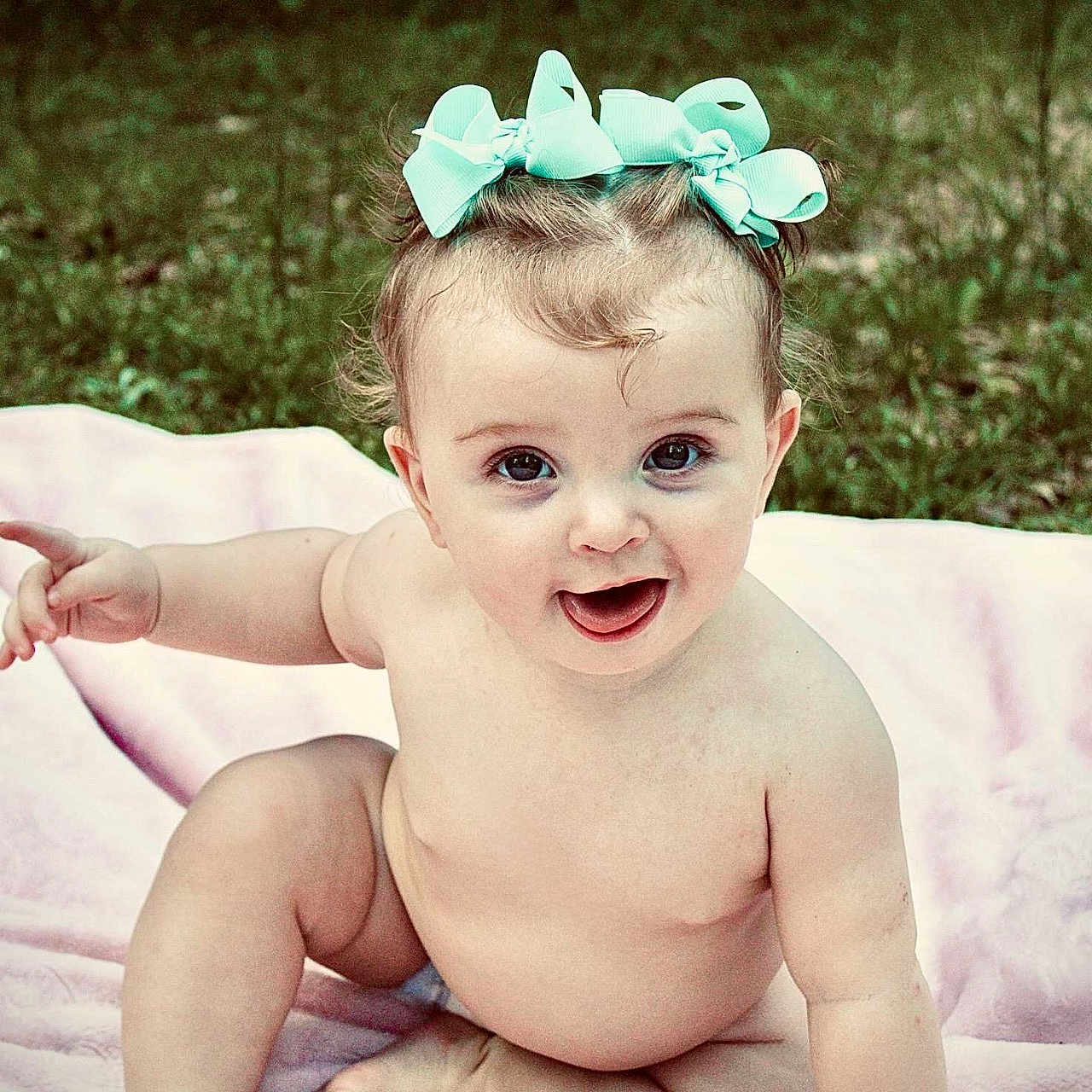 Swayzee joined the competition — help win amazing prizes! baby, blanket, bow, child, cute, expression, grass, hair_accessory, happy, infant, nature, outdoor, person, playful, portrait, sitting, skin, smiling, tongue_out, young