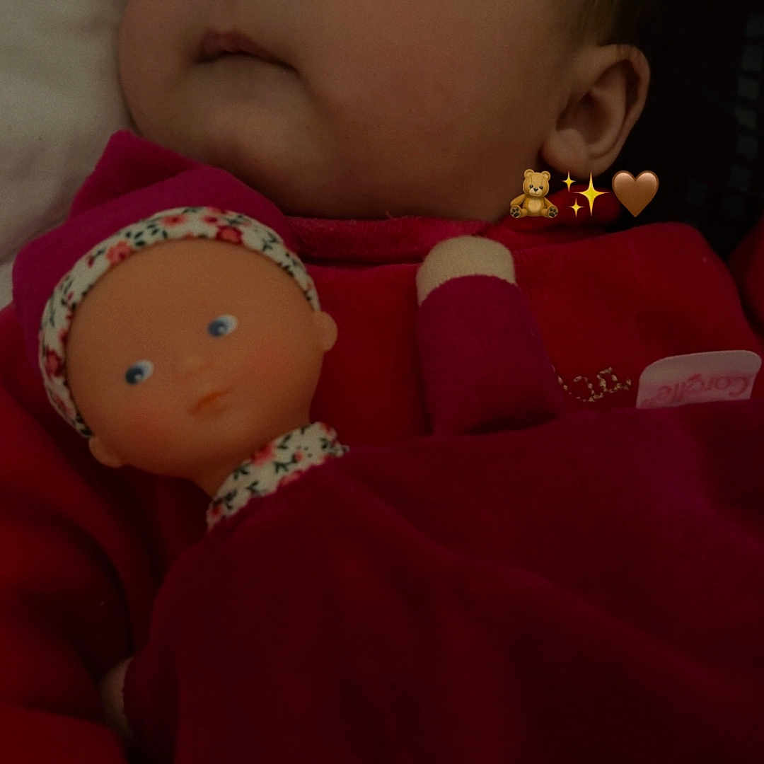 Aleïa a rejoint le concours — aidez-le/la à gagner de superbes lots ! baby, child, closeup, cozy, cute, doll, expression, face, headwear, indoor, infant, looking_away, person, plush, portrait, red_clothing, sleepwear, soft_lighting, toy, young_child