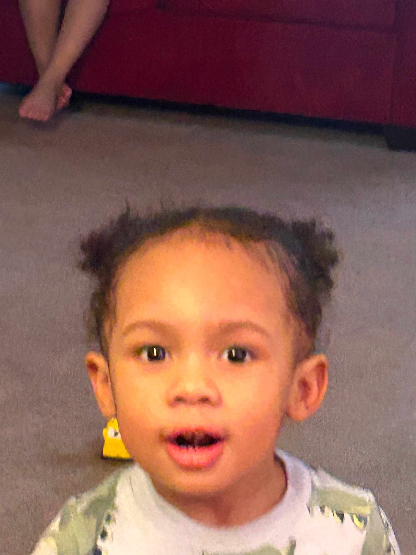 Ivanni joined the competition — help win amazing prizes! child, toddler, face, surprised, open_mouth, eyes, hair_puffs, ears, toy, carpet, living_room, couch, bare_foot, portrait, indoor, expression, clothing, person, young_child, smiling_ish