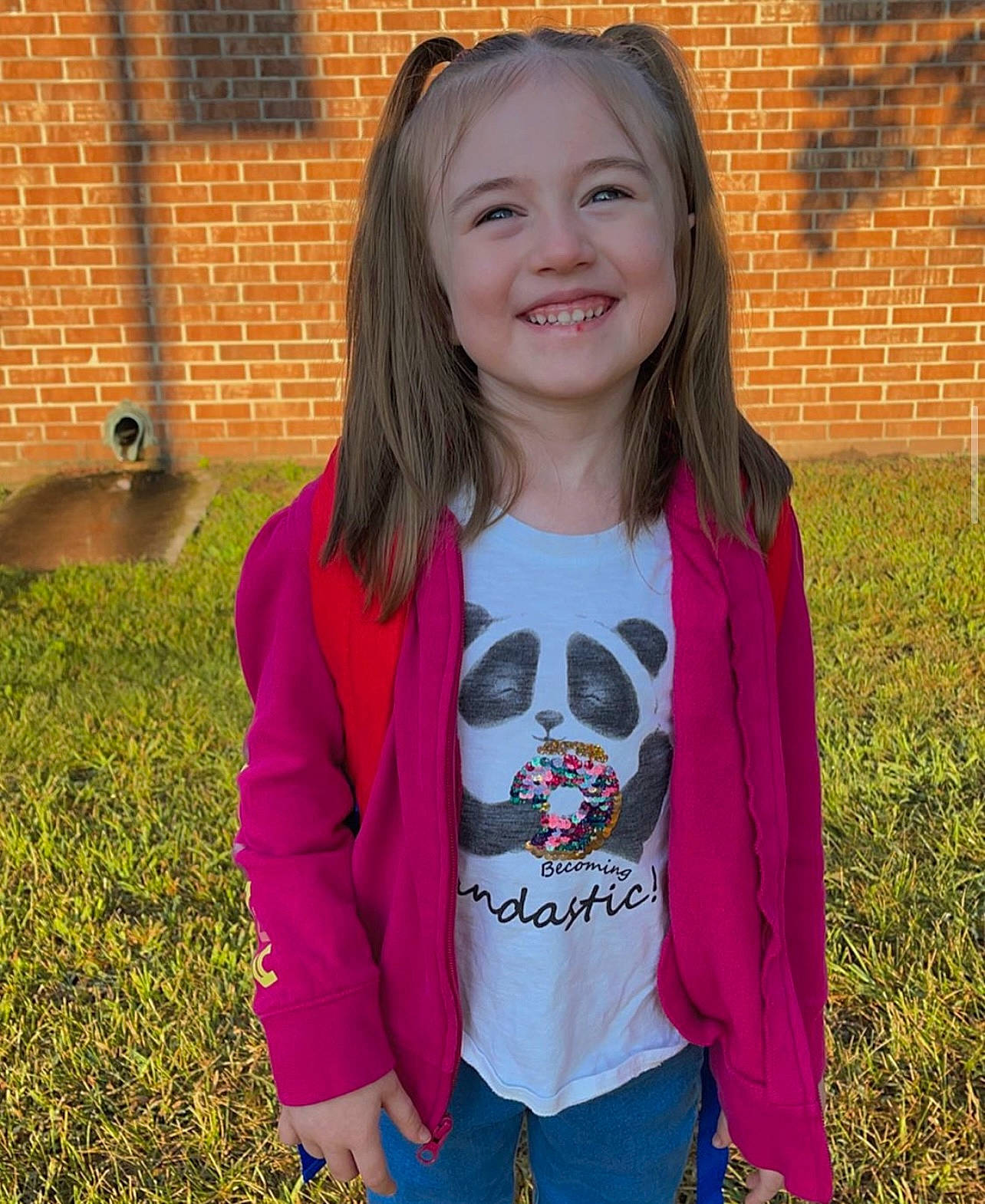 Lillian is registered to the contest to win money with this photo: brick, clothing, cool, face, grass, happy, head, iris, joy, leaf, magenta, outerwear, person, pink, plant, sleeve, smile, standing, street_fashion, t_shirt