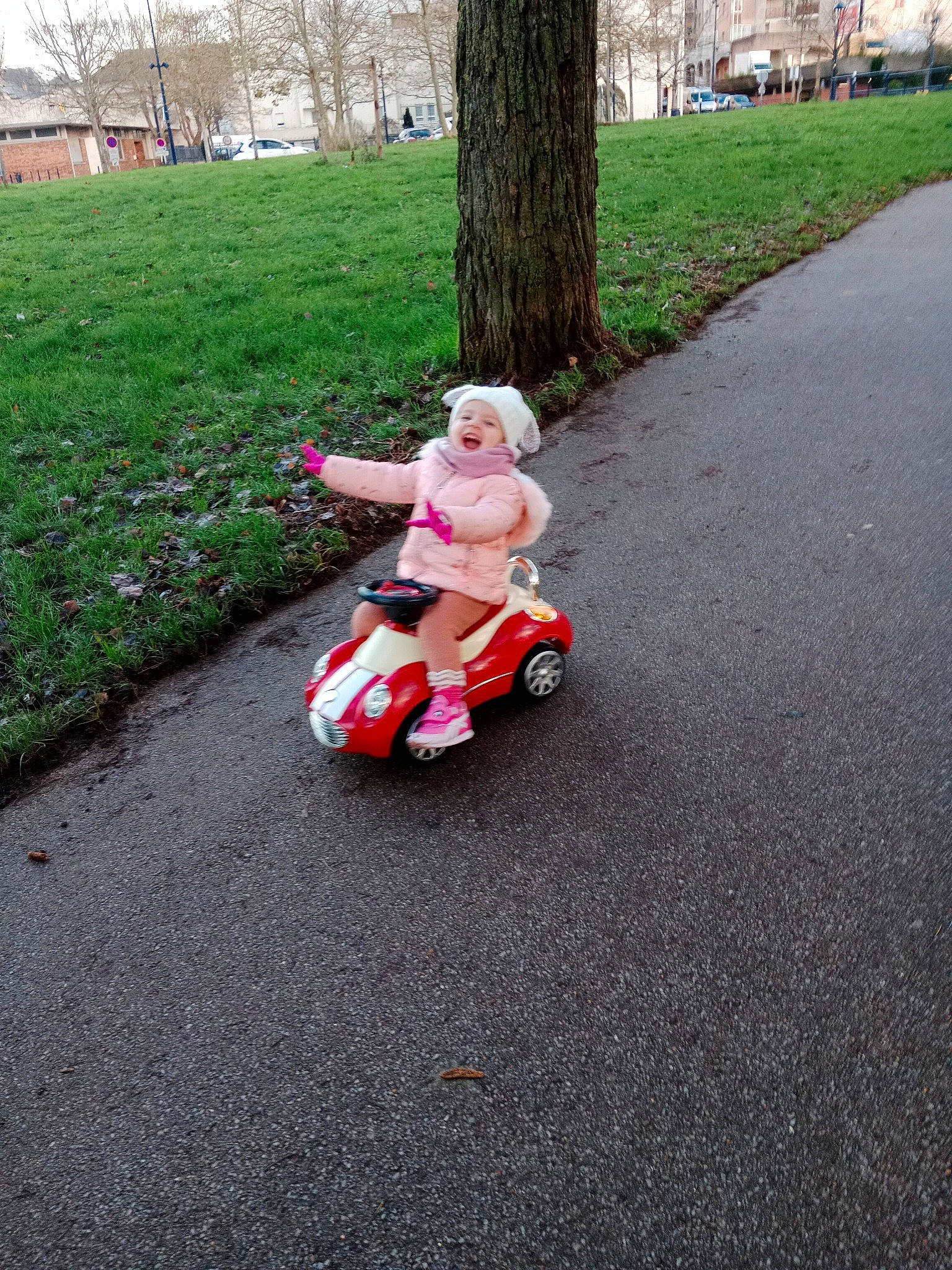 Lena participe au concours pour gagner de l'argent avec cette photo : asphalt, baby, driveway, grass, headwear, lawn, motor_vehicle, people_in_nature, person, plant, recreation, riding_toy, road, road_surface, rolling, sidewalk, tar, tire, toddler, toy