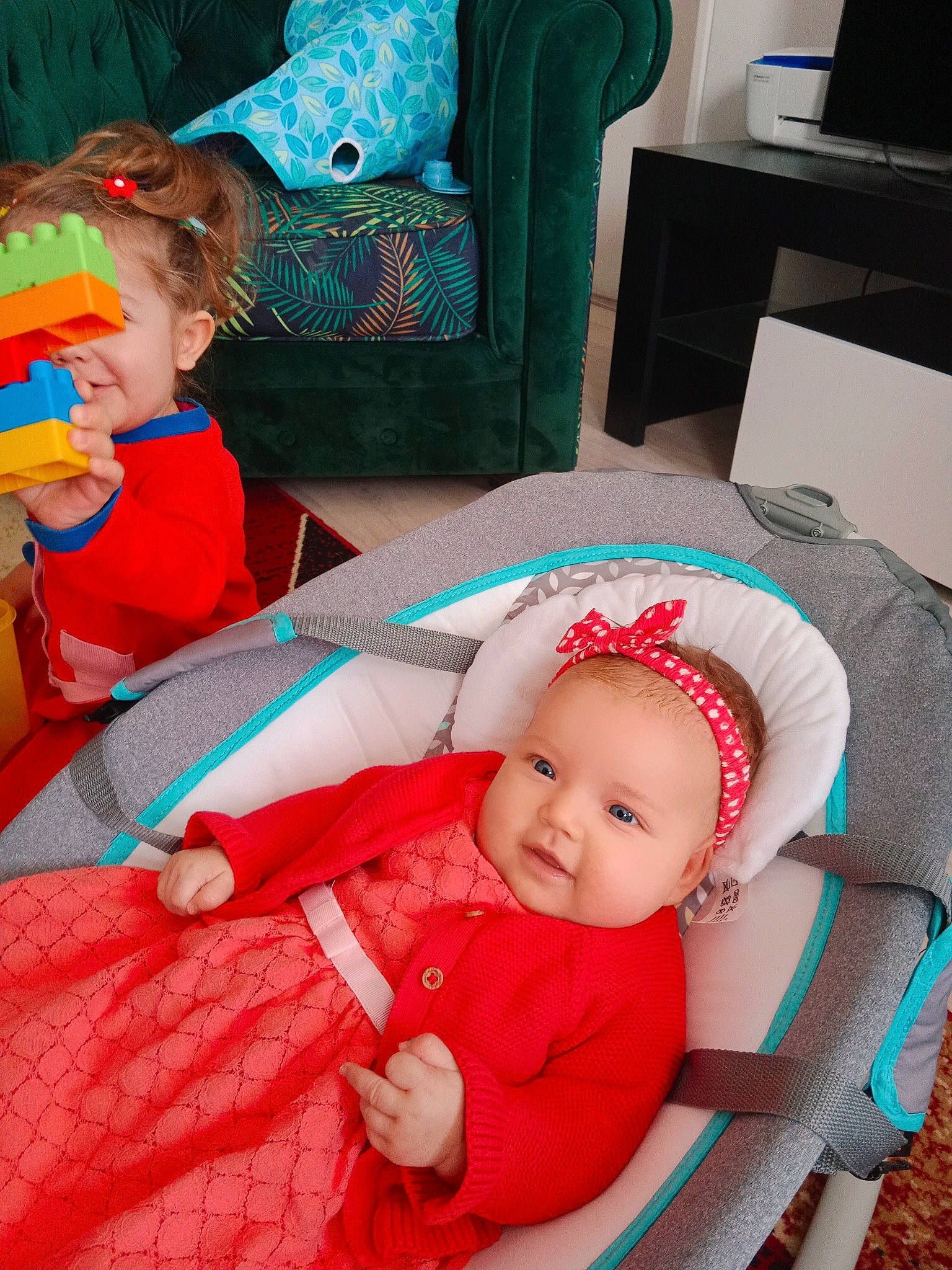 Lucia a rejoint le concours — aidez-le/la à gagner de superbes lots ! baby, baby_products, baby_toddler_clothing, blue, child, comfort, event, face, fictional_character, fun, green, happy, headwear, lap, person, pink, red, room, sitting, smile