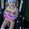 baby, child, stroller, smile, bow, dress, socks, feet, legs, blanket, outdoor, happy, person, infant, cute, clothing, seat, baby_carrier, headwear, portrait