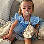 toddler, child, pacifier, blue_dress, blanket, couch, white_shoes, indoor, person, face, sitting, soft_texture, beads, clothing, footwear, comfort, young_child, cute, portrait, home