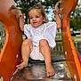 toddler, child, slide, playground, outdoor, sand, happy, smiling, barefoot, orange, clothing, shorts, white_top, person, park, metal_slide, handles, daylight, nature, fun