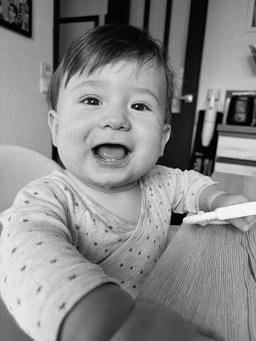 Charly a rejoint le concours — aidez-le/la à gagner de superbes lots ! baby, child, smiling, happy, face, drool, onesie, star_pattern, table, hand, indoor, highchair, monochrome, black_and_white, portrait, cute, infant, young_child, person, closeup