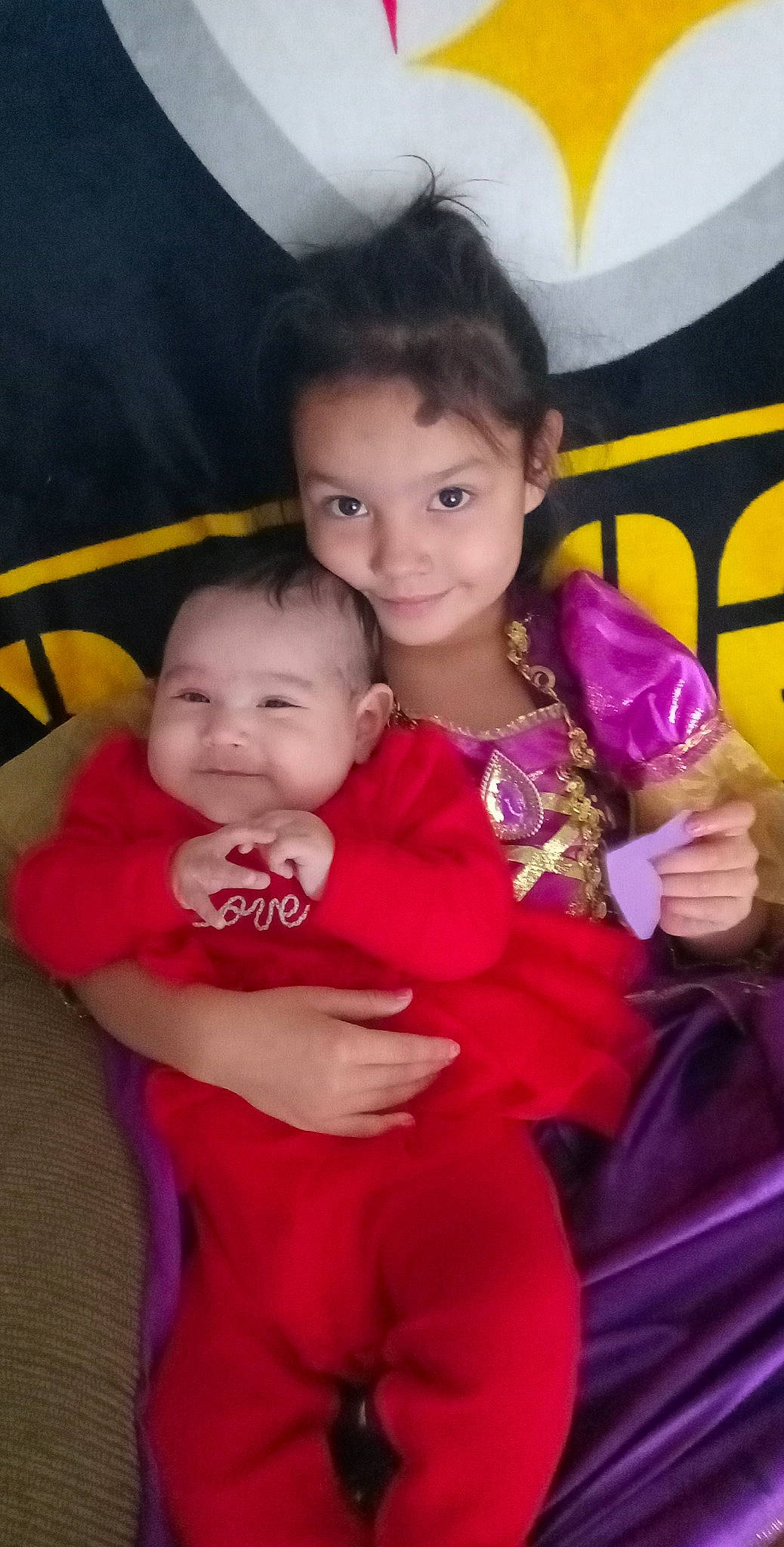 Joanna is registered to the contest to win money with this photo: arm, baby_toddler_clothing, comfort, eye, facial_expression, finger, fun, gesture, hand, happy, iris, joy, lap, mammal, person, pink, product, skin, smile, textile