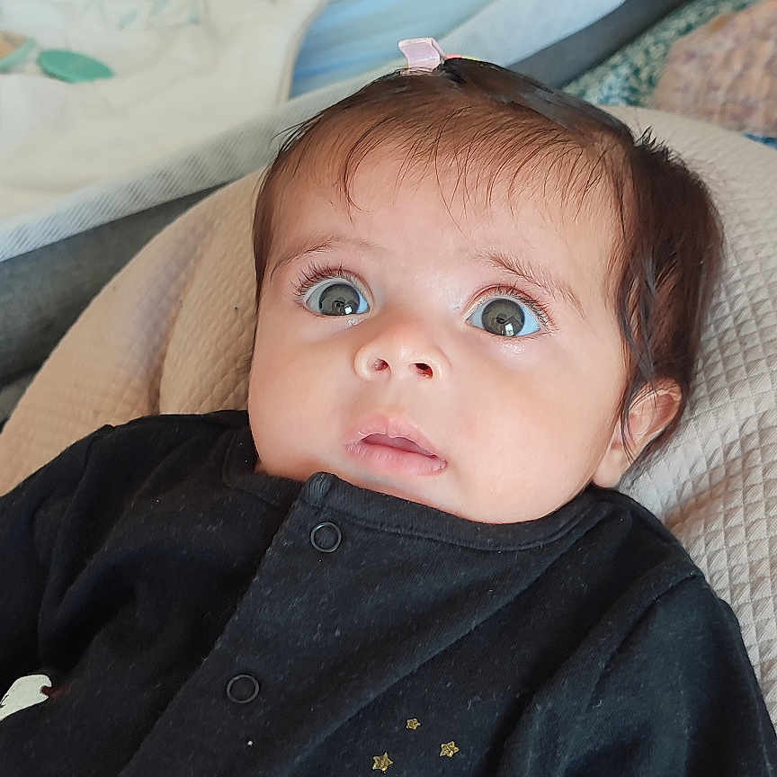 Faya a rejoint le concours — aidez-le/la à gagner de superbes lots ! apparel, baby, black_clothing, blanket, child, comfortable, cute, expression, eyes, face, hair_clip, home, indoors, infant, looking_up, portrait, seated, soft_fabric, swan_print, young