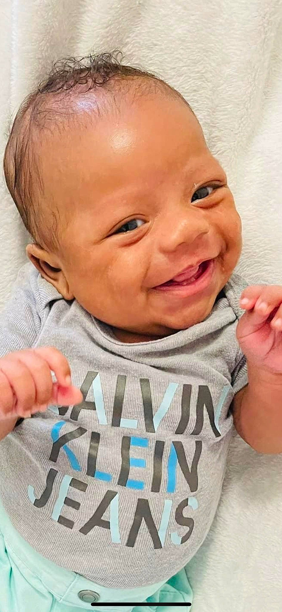 Osiah is registered to the contest to win money with this photo: arm, baby, baby_toddler_clothing, cheek, chin, eye, eyebrow, facial_expression, hairstyle, hand, human_body, joy, lip, mouth, muscle, neck, nose, person, product, skin