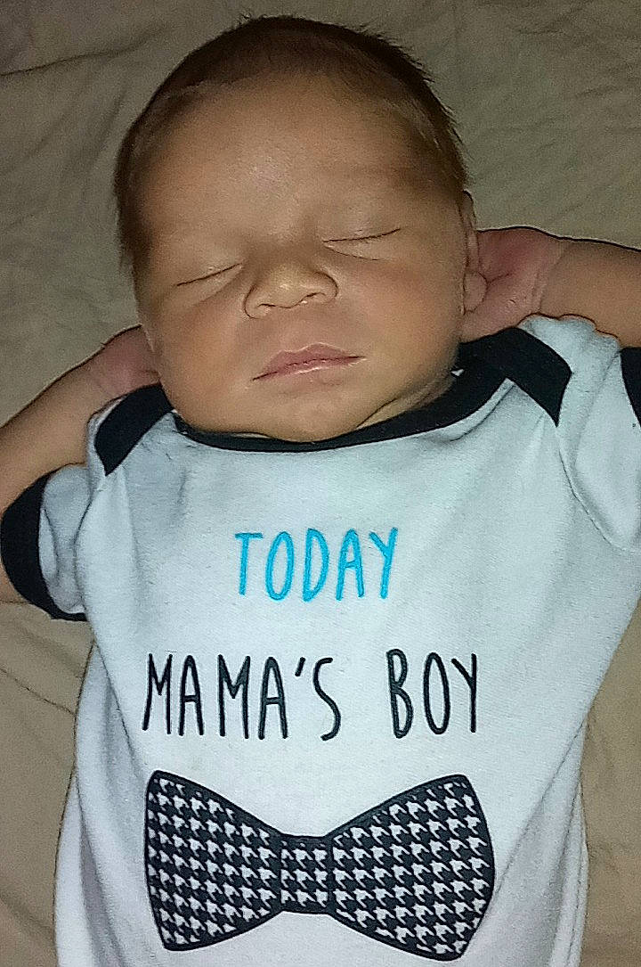 Giovanni is registered to the contest to win money with this photo: arm, baby_toddler_clothing, cheek, comfort, finger, gesture, hair, happy, joint, mammal, mouth, neck, nose, organ, outerwear, person, product, sleeve, t_shirt, textile