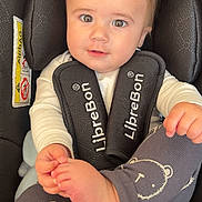 Oscar joined the competition — help win amazing prizes! baby, child, car_seat, infant, face, eyes, clothing, white_shirt, leggings, bear_pattern, foot, hand, hair, seat_belt, black, safety, cute, portrait, indoor, closeup