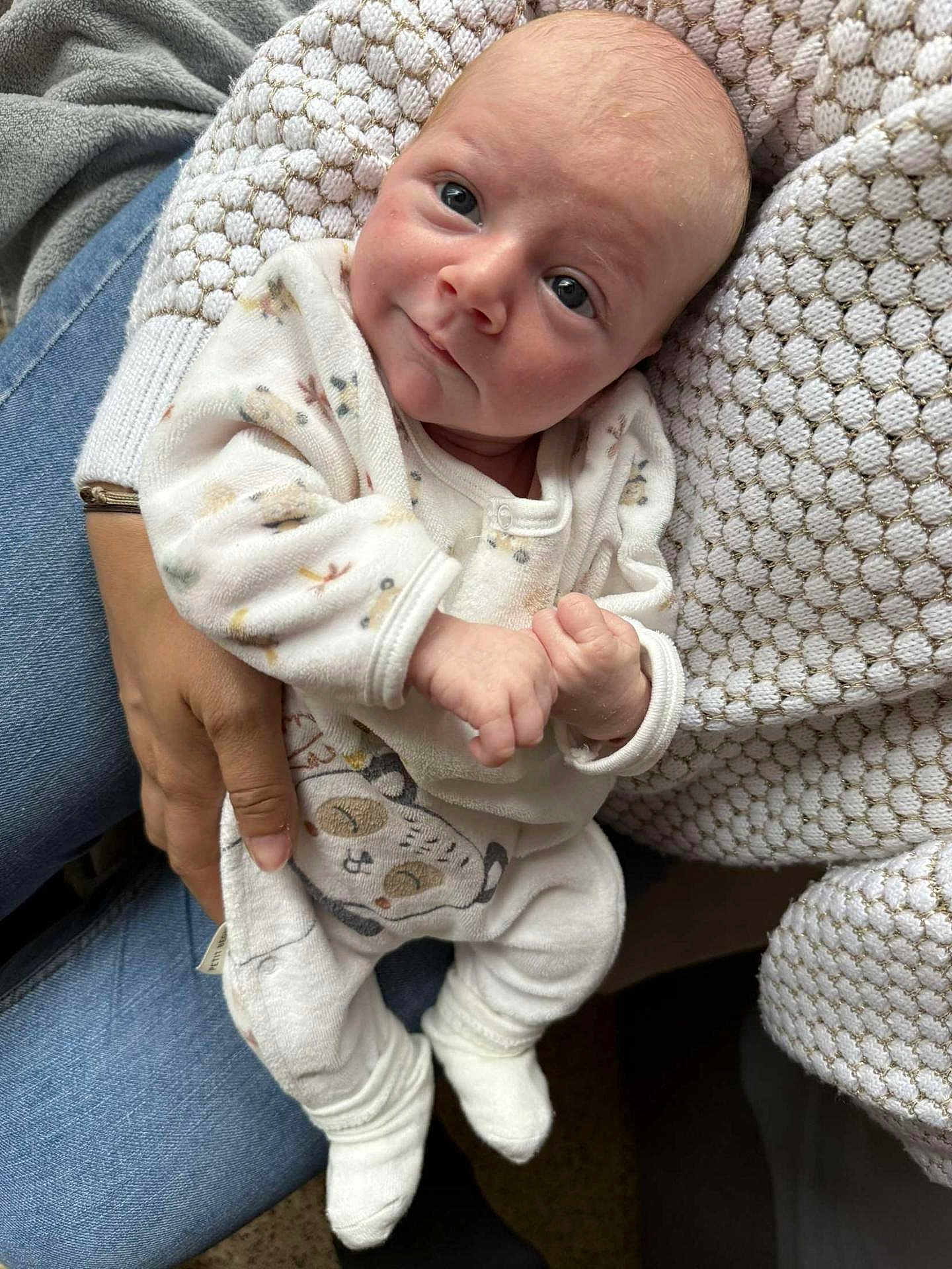 Victoria participe au concours pour gagner de l'argent avec cette photo : baby, infant, person, clothing, pajamas, hand, sitting, adult, jeans, sweater, texture, face, eyes, smile, cozy, indoor, cute, animal_print, footwear, holding