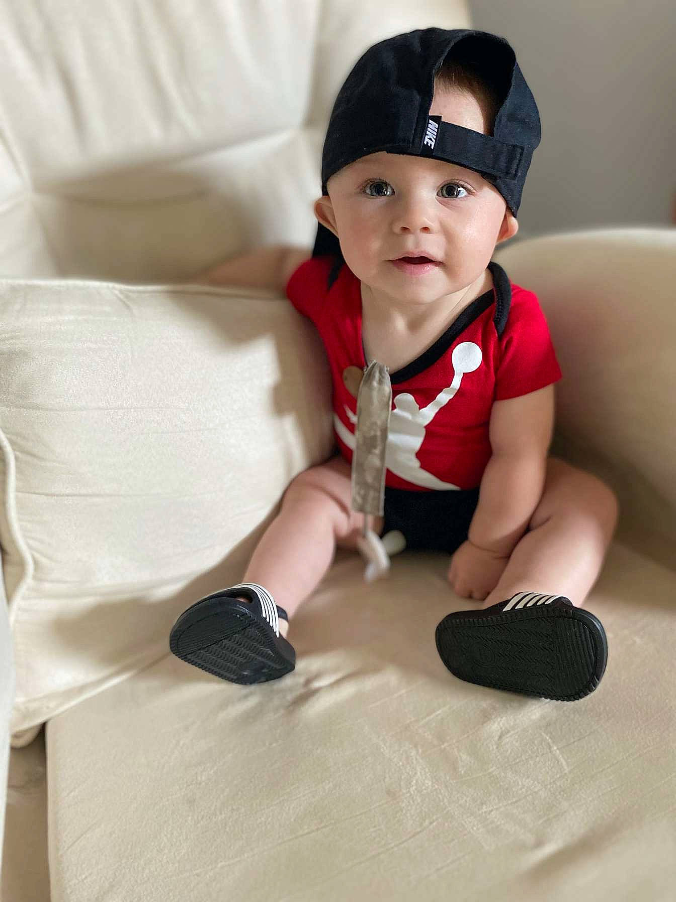 Atlas is registered to the contest to win money with this photo: baby, baby_toddler_clothing, cap, carmine, child, comfort, finger, flooring, happy, hat, headwear, human_body, human_leg, knee, linens, person, sitting, sleeve, sock, textile