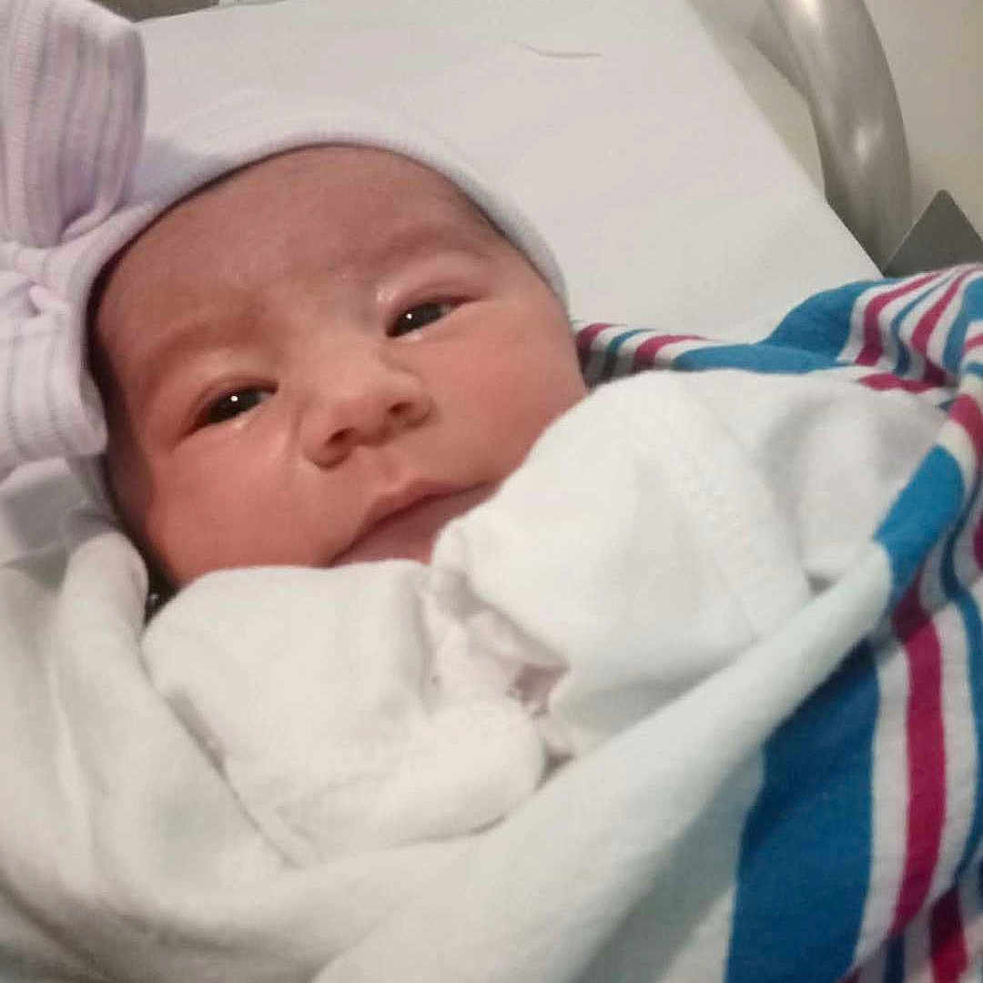 Octavia is registered to the contest to win money with this photo: newborn, baby, hospital, blanket, hat, bow, bassinet, bed, face, person, infant, sleeping, cute, wrapped, clothing, newborn_baby, healthcare, lying_down, resting, indoors