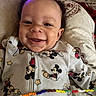baby, beaded_necklace, beads, child, closeup, clothing, cute, face, happy, indoors, infant, joyful, lying_down, mickey_mouse, onesie, patterned, person, pillow, portrait, smiling