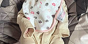 Lily joined the competition — help win amazing prizes! baby, bib, blanket, child, clothing, comfort, cute, expression, eyes, face, indoor, infant, newborn, pajamas, person, portrait, quilt, sitting, soft, young