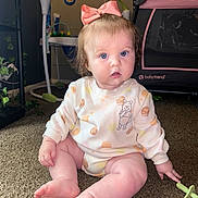 Octavia is registered to the contest to win money with this photo: baby, child, bow, blue_eyes, carpet, clothing, couch, face, floor, furniture, indoor, infant, nursery, outfit, playpen, sitting, toy, winnie_the_pooh, young_child, pink_bow